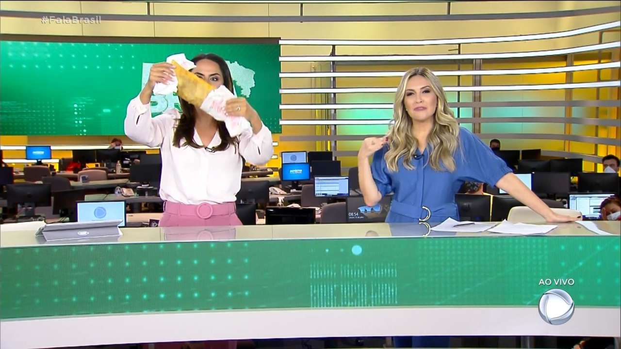 Momento em que Carla Cecato parte o pastel no Fala Brasil