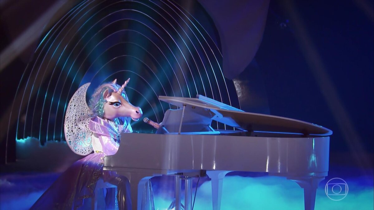 Fantasia de Unicórnio se apresenta no palco do The Masked Singer Brasil tocando Piano