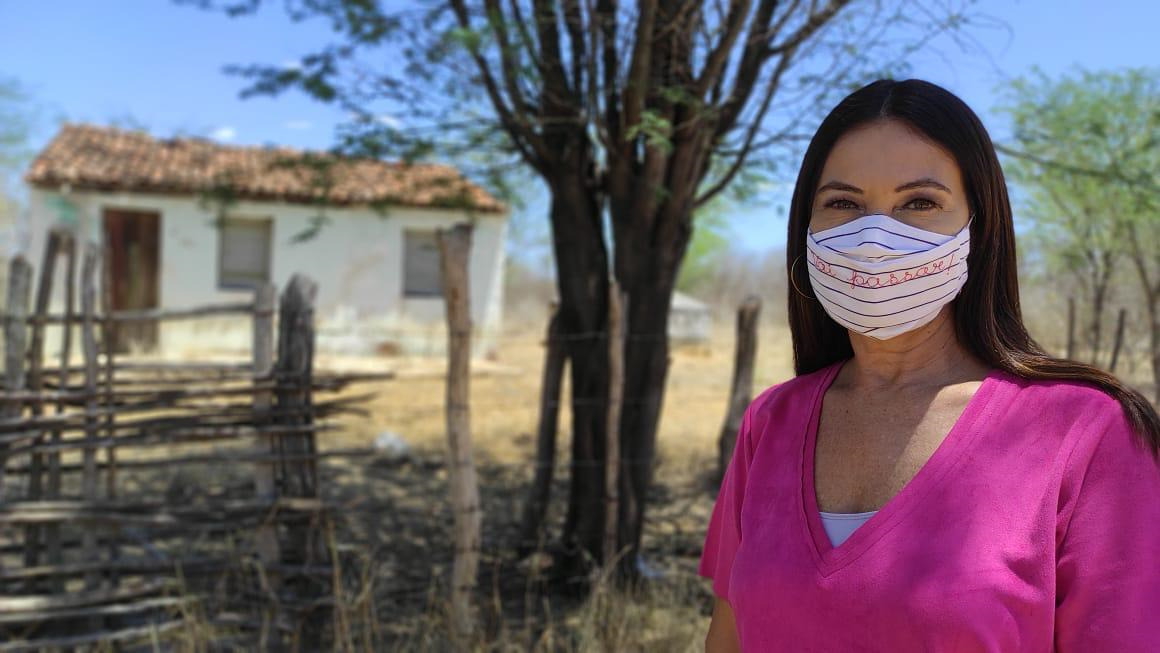 Repórter Beatriz Castro em bastidores da gravação do Globo Repórter no sertão nordestino. Ela veste uma blusa rosa e uma máscara branca e rosa