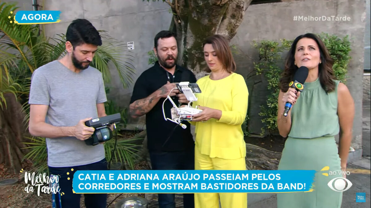 Cátia Fonseca pilotando um drone, ao lado de Adriana Araújo e os rapazes da equipe da Band, no estacionamento da emissora