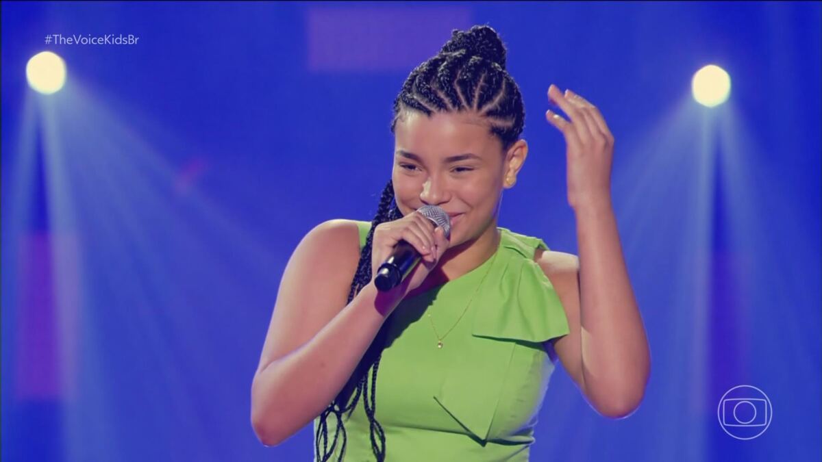 Clara Casto de vestido verde se apresentando no The Voice Kids 8