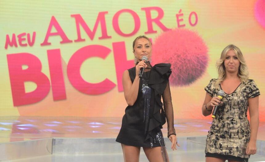 Sabrina Sato, de vestido preto ao lado de Giovana, que está com um vestido mais discreto e claro. As duas gravam o quadro Meu Amor é o Bicho, no Programa da Sabrina