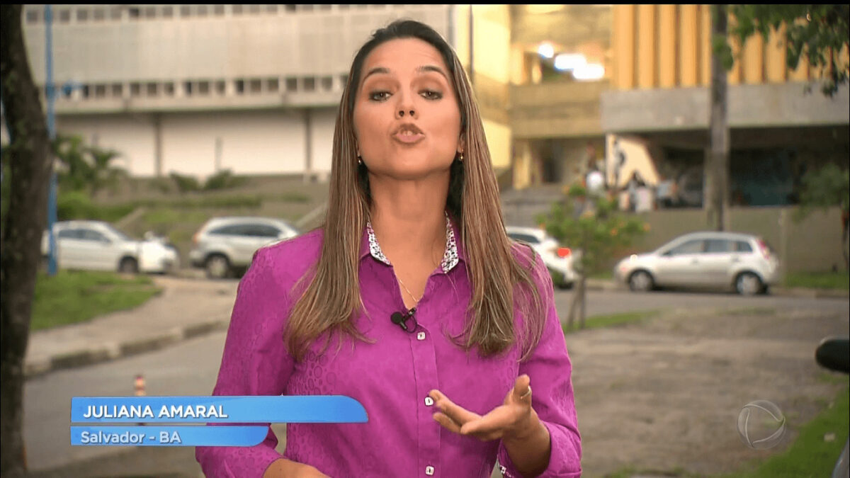 Repórter Juliana Amaral levanta o braço durante reportagem do Jornal da Record