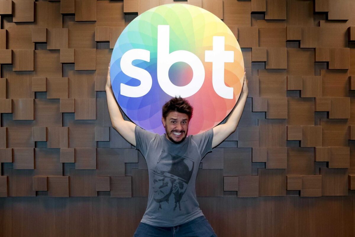 Oscar Filho brinca com o logo do SBT, durante a assinatura do contrato