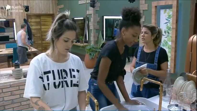 Tati, Sabrina e Hari conversam enquanto lavam os pratos de A Fazenda