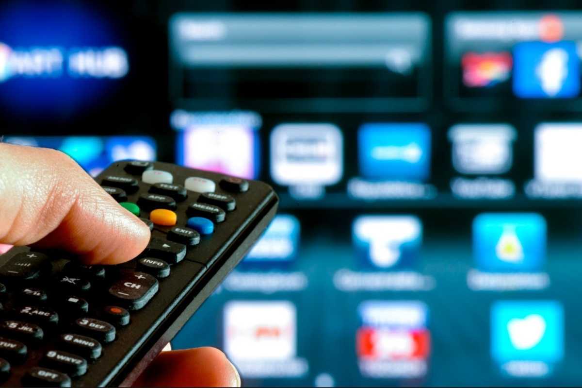 Mão com controle remoto apontando para a televisão