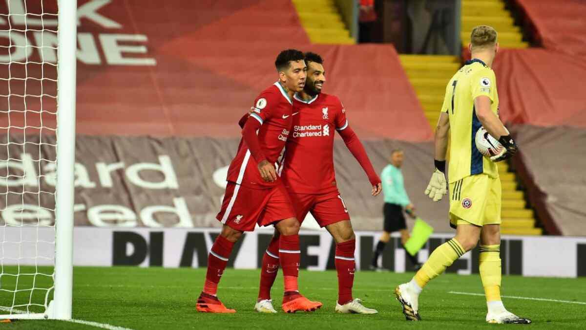 Jogadores Firmino e Salah comemorando um gol com a camisa do Liverpool