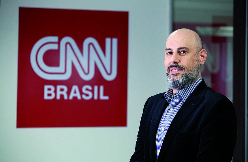 Douglas Tavolaro em frente a um banner com o logo da CNN Brasil