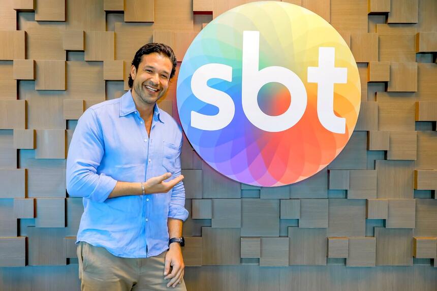 Sérgio Marone aponta para o Logo do SBT no dia da assinatura de contrato