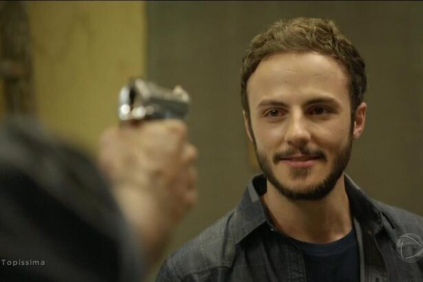 Pedro (Felipe Cardoso) apontando uma arma para Bruno (Miguel Roncato) em cena da novela Topíssima