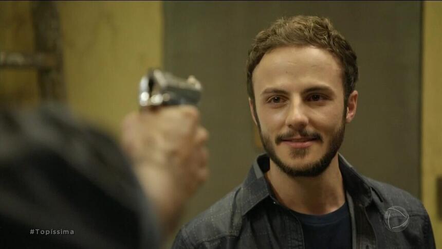 Pedro (Felipe Cardoso) apontando uma arma para Bruno (Miguel Roncato) em cena da novela Topíssima