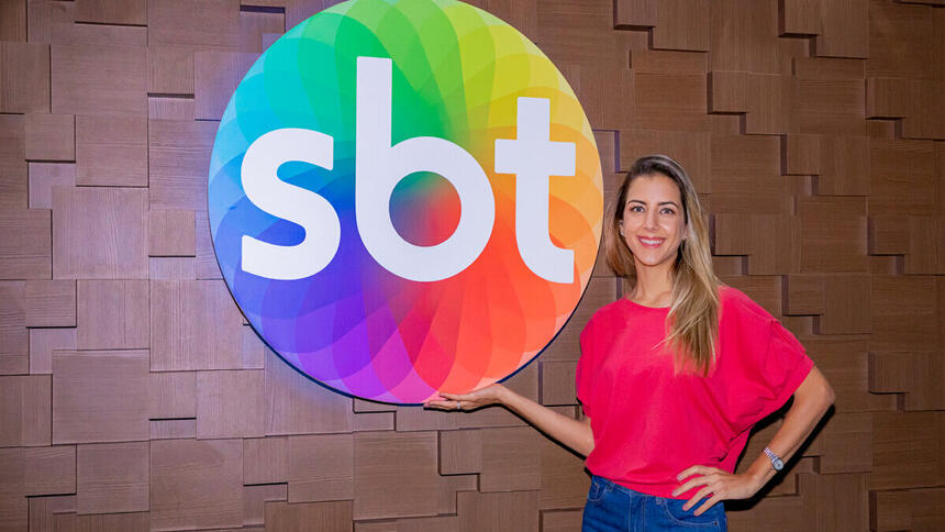 Domitila Becker na sede do SBT, em frente a logo do canal