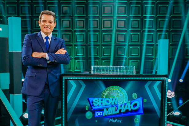 Celso Portiolli ao lado da tela com o logo do Show do Milhão