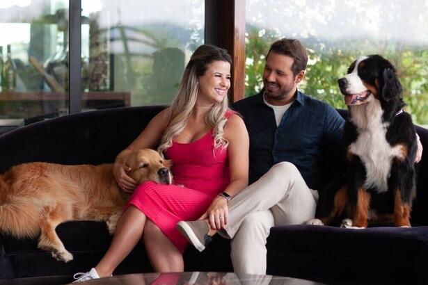 Dony de Nuccio sentando em um sofá ao lado da esposa e dos seus dois cachorros