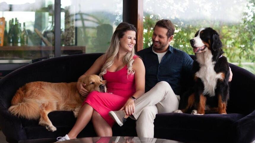 Dony de Nuccio sentando em um sofá ao lado da esposa e dos seus dois cachorros