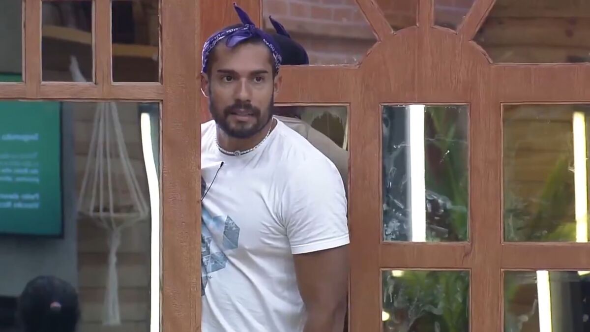 Bil, posicionado a frente da porta da sede de A Fazenda, lendo comunicado da produção