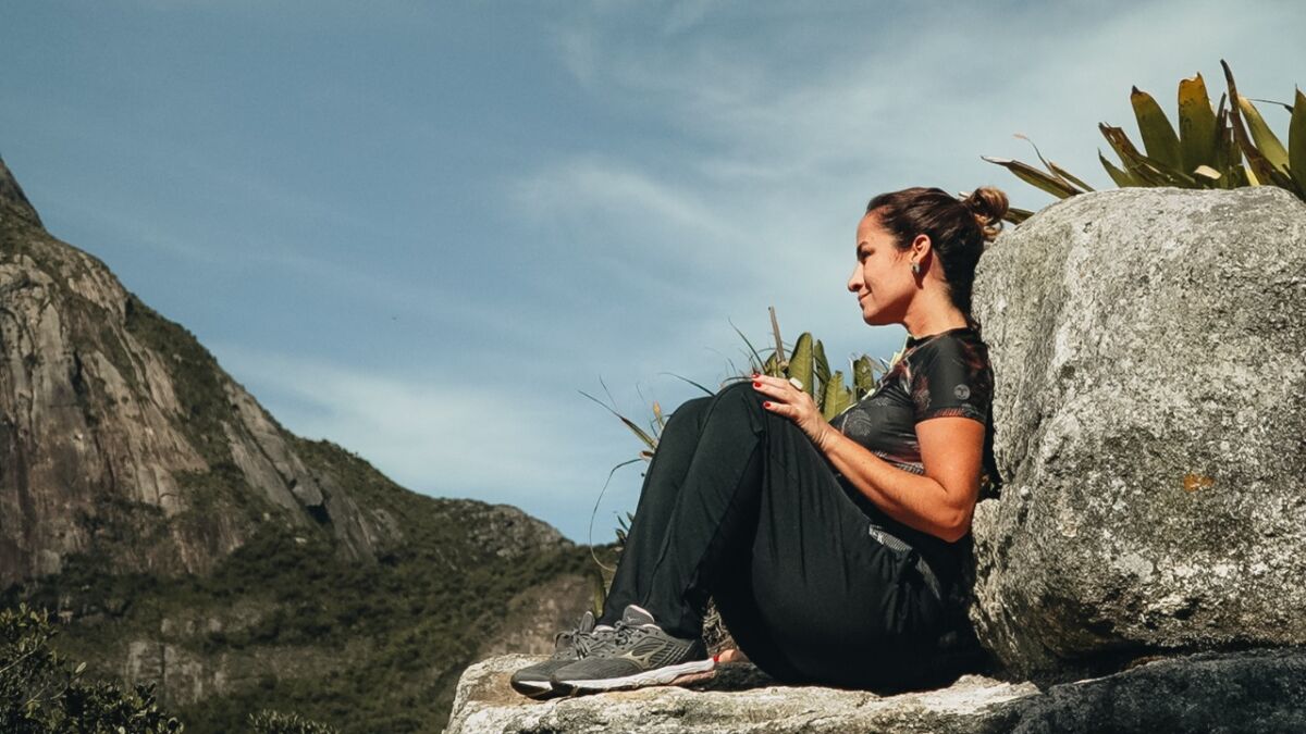 Fernanda Graell sentada em uma pedra no Parque Estadual dos Três Picos, em gravação para o Globo Repórter