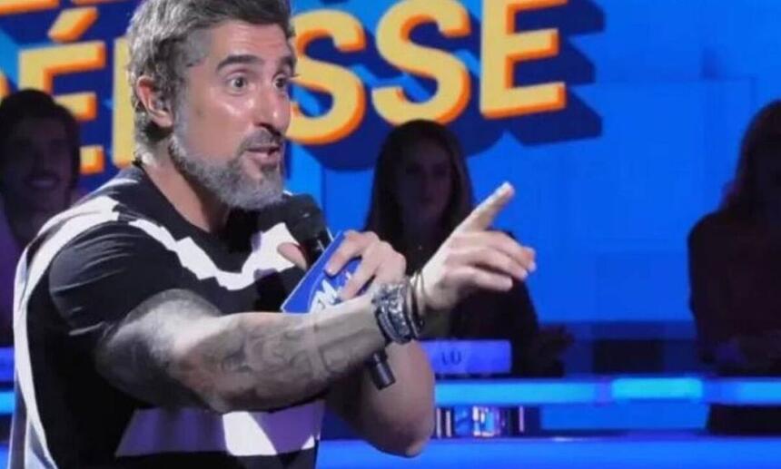 Marcos Mion durante o Caldeirão, nos estúdios do programa, com os braços a mostra e mostrando as tatuagens