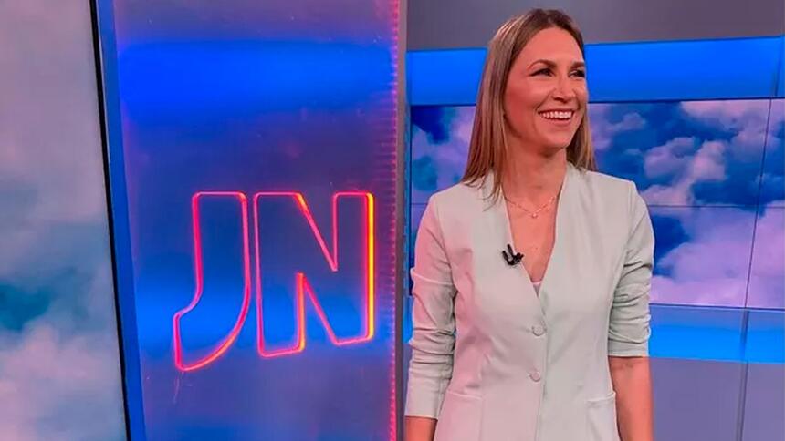 Anne Lottermann sorrir em frente ao logo do Jornal Nacional