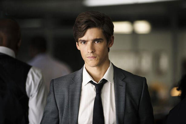 Brenton Thwaites de terno e gravata em cena da série 'Titãs'