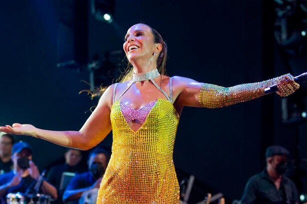 Ivete Sangalo de vestido amarelo e com os braços abertos em show realizado em Natal, Rio Grande do Norte