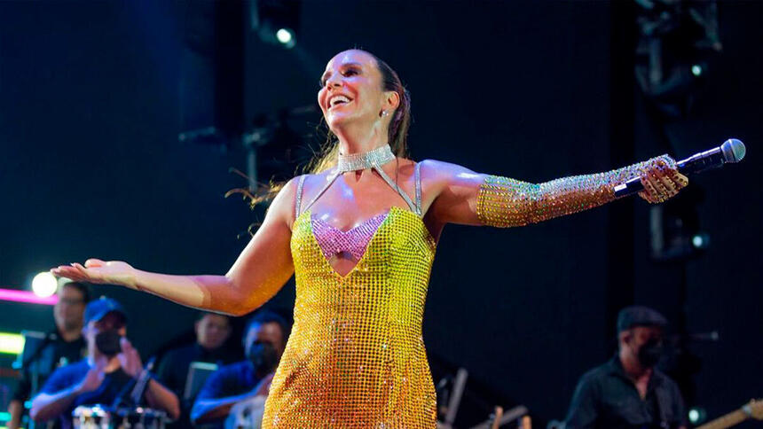 Ivete Sangalo de vestido amarelo e com os braços abertos em show realizado em Natal, Rio Grande do Norte