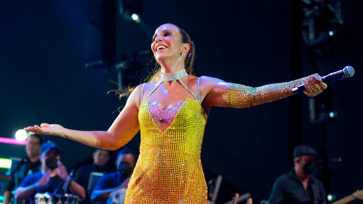 Ivete Sangalo de vestido amarelo e com os braços abertos em show realizado em Natal, Rio Grande do Norte