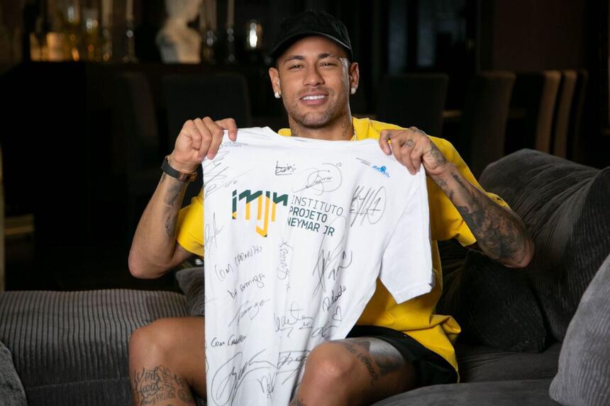 Neymar Jr exibe uma camisa toda assinada