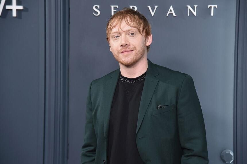 Rupert Grint posa para foto com terno verde e camisa preta