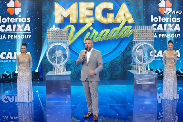 Apresentador Luigi Baricelli ao lado dos globos do sorteio da mega da virada 2021