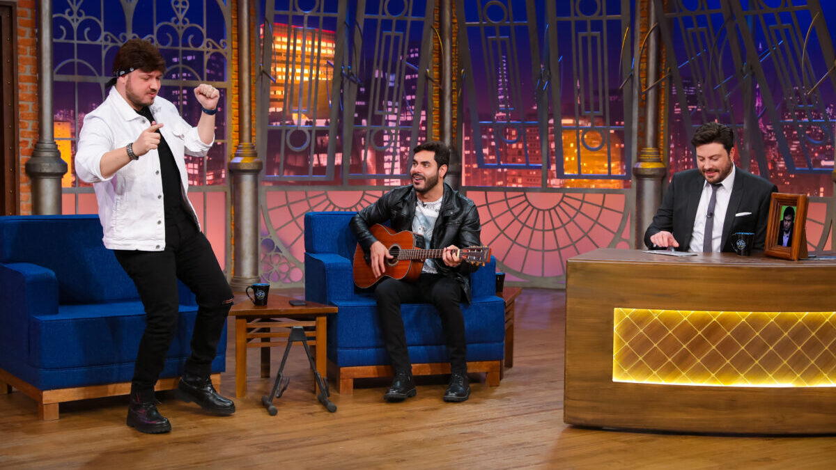 Israel dançando, Roldolffo tocando violão sentado, ao lado de Danilo Gentili nos estúdios do The Noite no SBT