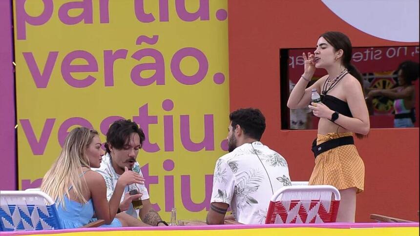 Rodrigo de costas, Eliezer e Bárbara sentados e Jade em pé chupando picolé durante ação no BBB 22.