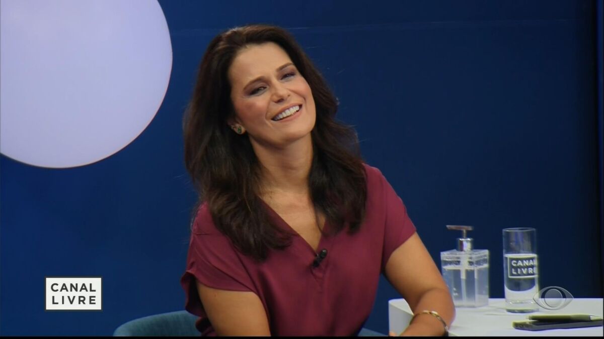 Adriana Araújo sorrir, sentada na bancada do Canal Livre, em sua estreia na Band