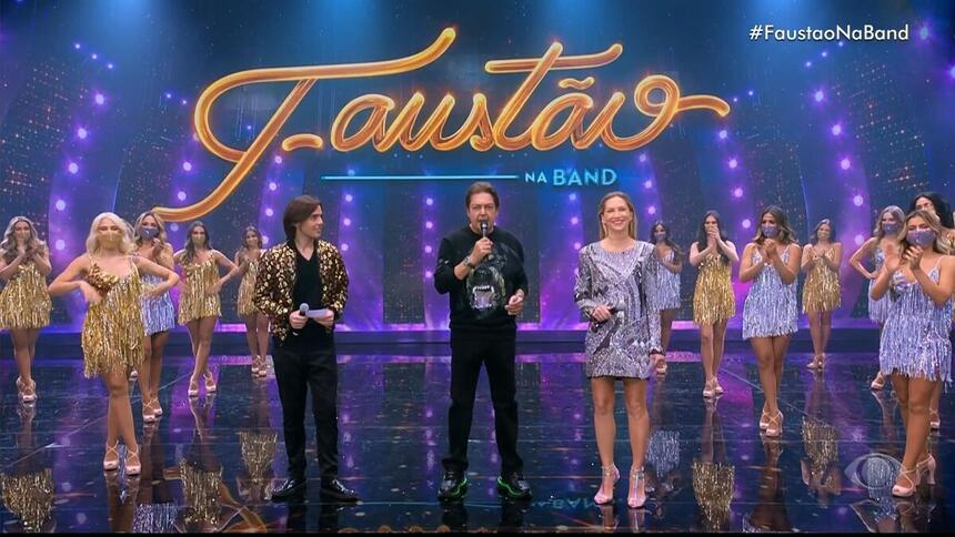 João Guilherme, Faustão e Anne Lotterman nos estúdios do programa Faustão Na Band, lado a lado, com as bailarinas ao fundo