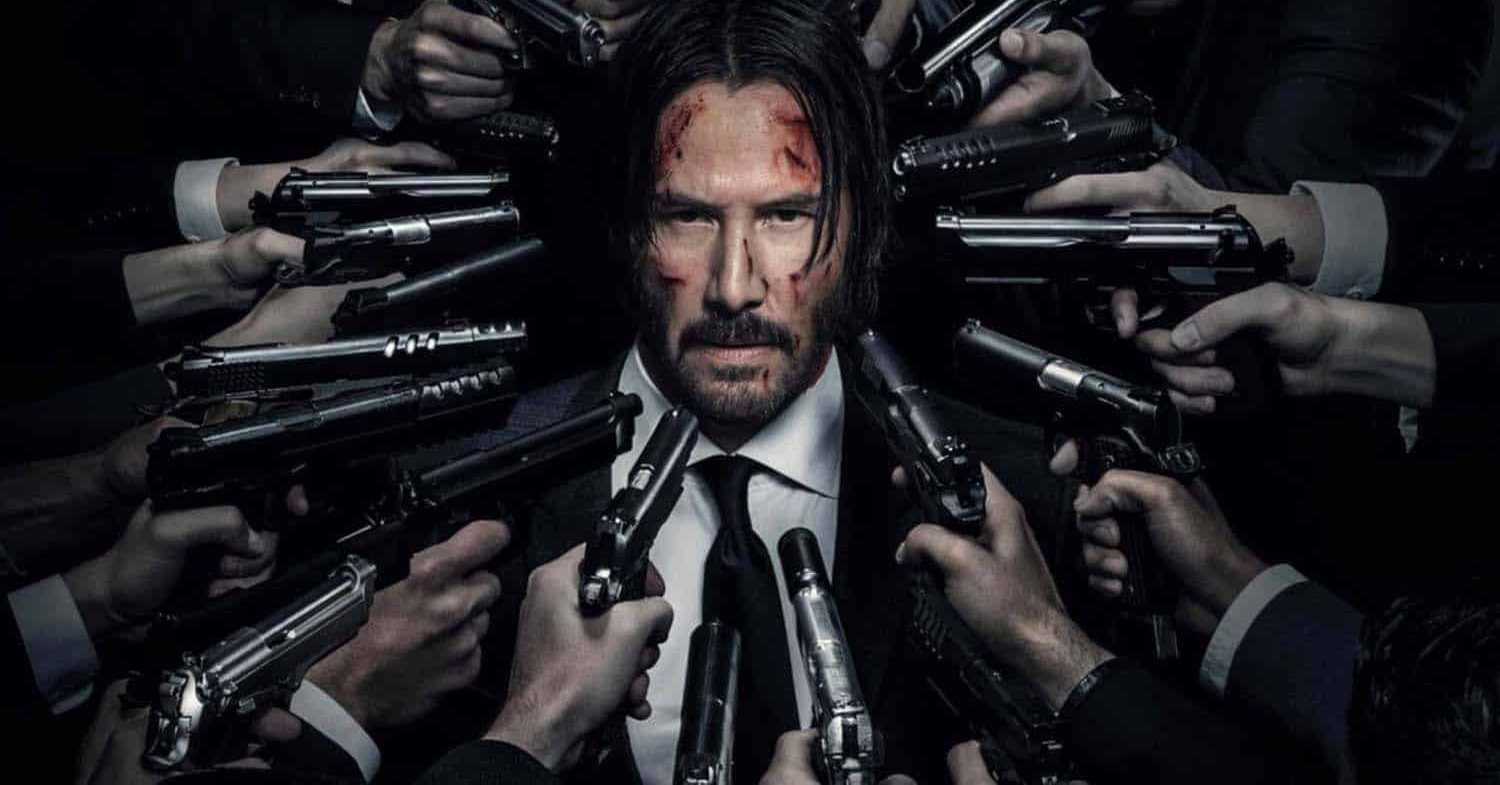 Keanu Reeves em cena do filme John Wick: Um Novo Dia Para Matar, com várias armas apontando para ele