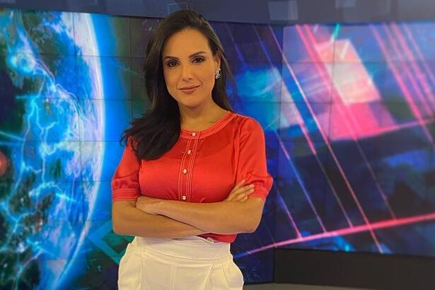 Márcia Dantas em pé, com os braços cruzados, nos estúdios do SBT Brasil