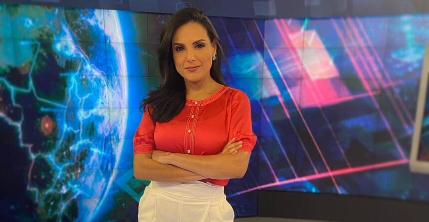 Márcia Dantas em pé, com os braços cruzados, nos estúdios do SBT Brasil