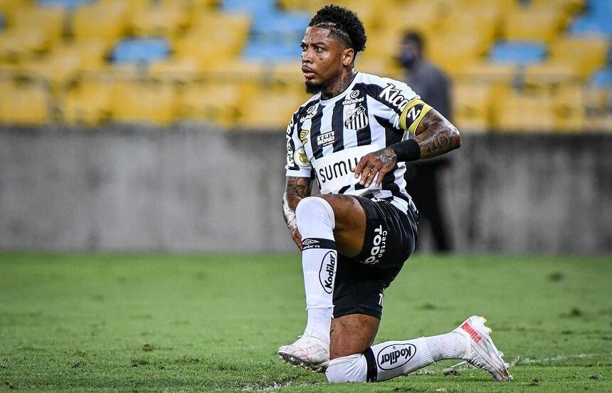 Marinho com a camisa do Santos, ajoelhado no gramado