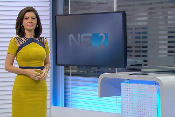 Meiry Lanunce vestido amarelo apresentado o NE2, em frente ao telão nos estúdios da Globo Nordeste