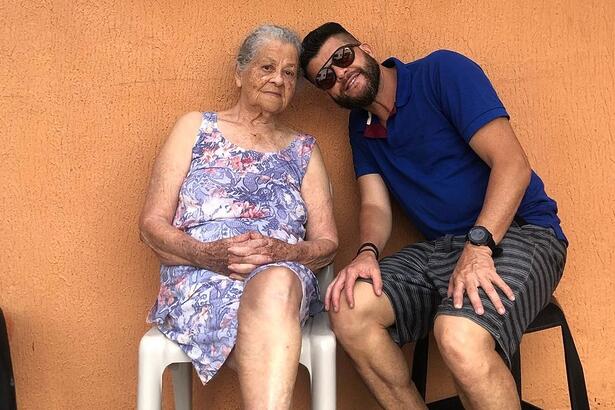 Odinei Ribeiro sentando ao lado de sua mãe, com as duas cabeças se encontrando