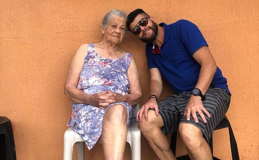 Odinei Ribeiro sentando ao lado de sua mãe, com as duas cabeças se encontrando