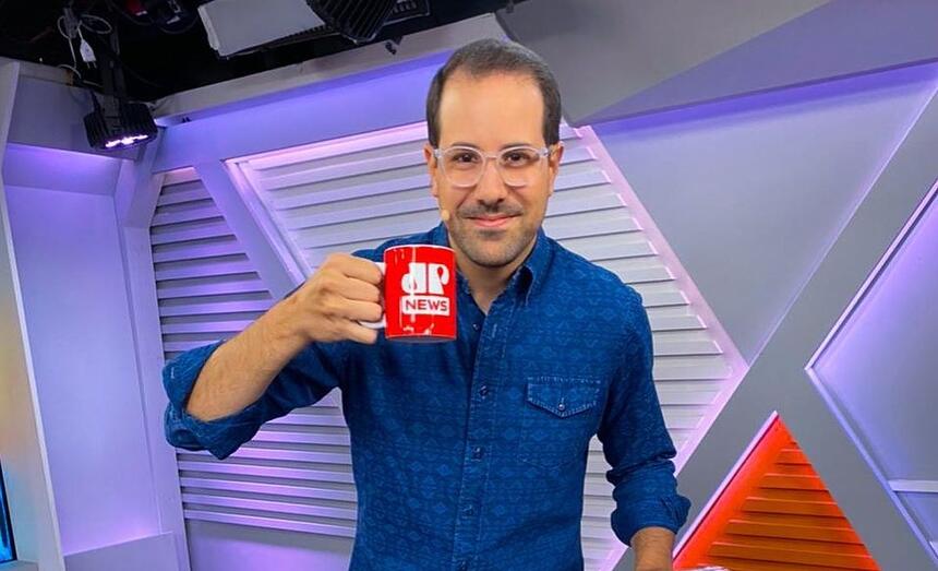 Paulo Mathias vestindo uma blusa azul e com uma caneca na mão