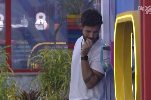 Rodrigo em pé próximo ao Big Fone do BBB 22.