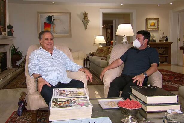 Ronnie Von sentado na sala de sua casa, ao lado do repórter da Record TV, em entrevista para o Domingo Espetacular