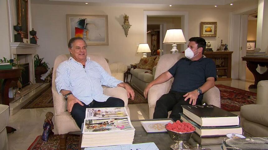 Ronnie Von sentado na sala de sua casa, ao lado do repórter da Record TV, em entrevista para o Domingo Espetacular