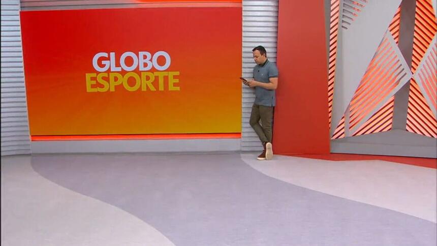 Tiago Medeiros mexendo no celular ao fundo dos estúdios do Globo Esporte PE