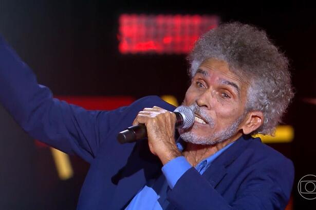 Arlindo Moita segura o microfone em apresentação no palco do The Voice+