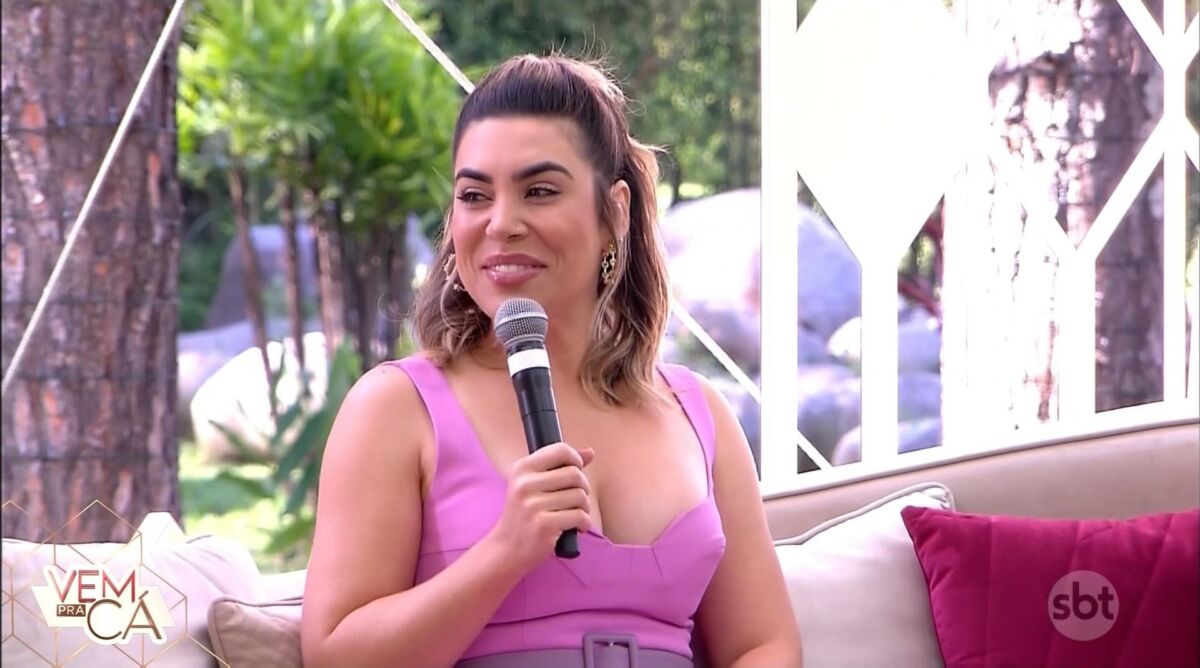 Naiara Azevedo de vestido rosa sentada no sofá do programa Vem Pra Cá