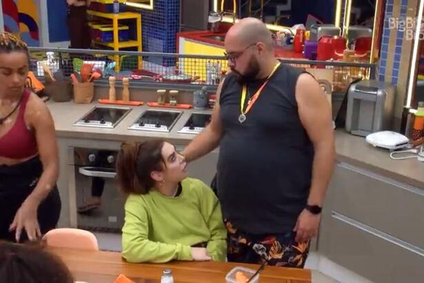 Naiara sentada e Tiago em pé, conversam na cozinha da xepa do BBB 22.