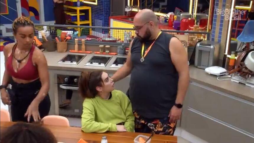 Naiara sentada e Tiago em pé, conversam na cozinha da xepa do BBB 22.